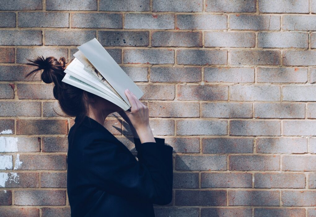 woman covering her face with white book